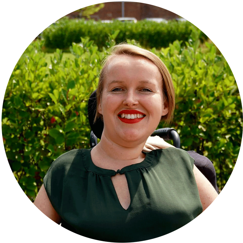 Patrizia-Kubanek Patrizia Kubanek, Mitarbeiterin von Pat.nrw sitzt vor einer grünen Hecke und lächelt in die Kamera